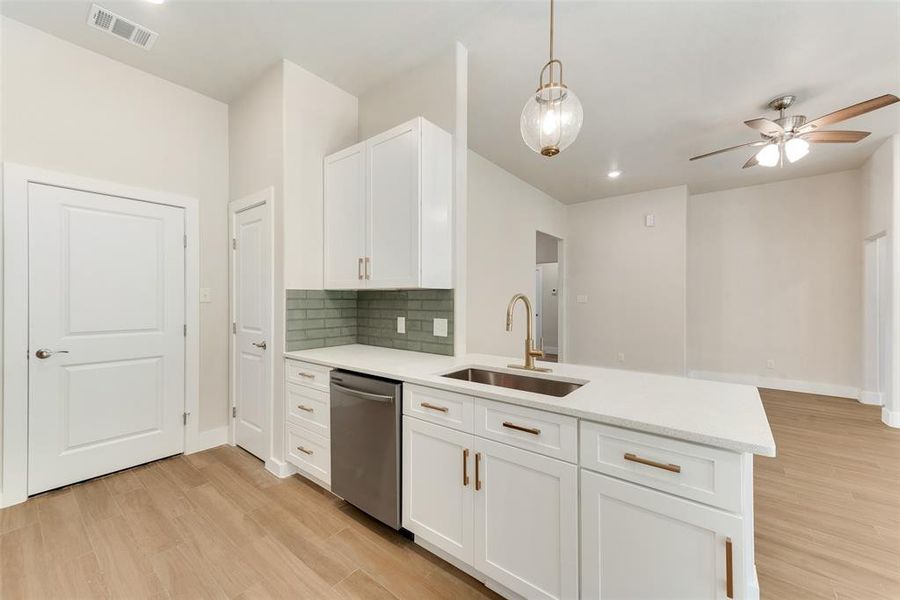 Kitchen featuring white cabinets, light hardwood / wood-style flooring, sink, and stainless steel dishwasher