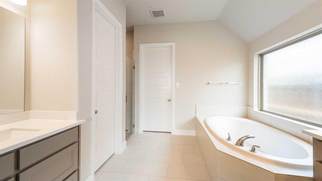 Bathroom featuring plus walk in shower, vanity, tile patterned floors, and vaulted ceiling