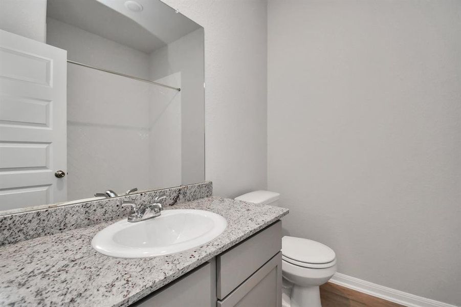 This secondary bathroom features a clean, modern design with a tiled shower and tub combo, a granite countertop, and a sleek under-mount sink. The bright white finishes create a fresh, airy feel, complemented by durable hardware and a five-panel door for added style.