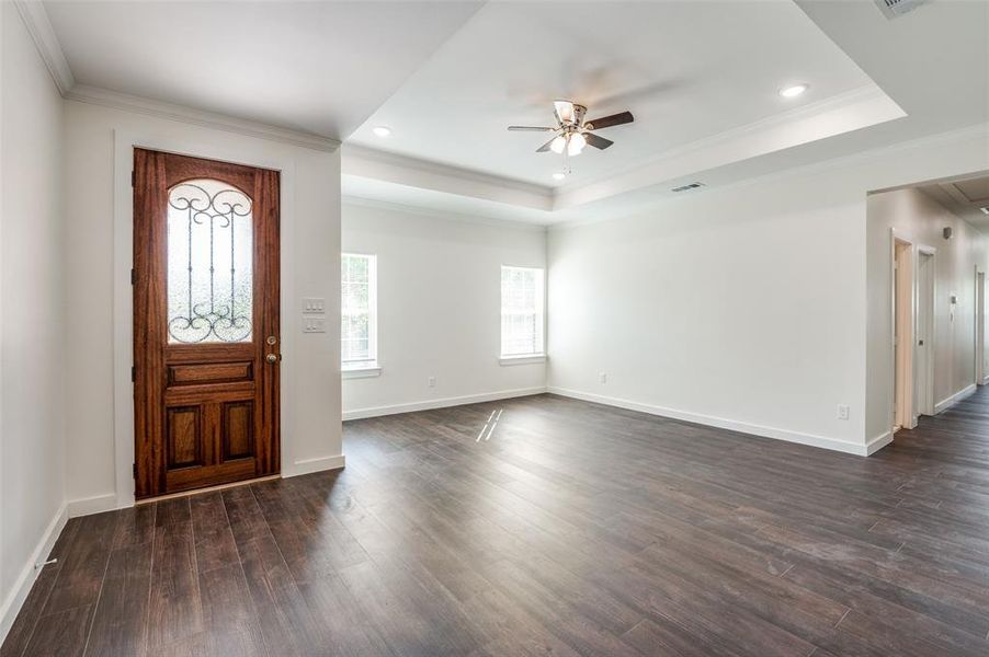 Entrance foyer featuring ceiling fan, a tray ceiling, ornamental molding, and dark hardwood / wood-style flooring