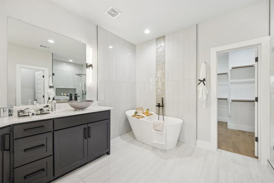 Bathroom featuring tile patterned flooring, shower with separate bathtub, and vanity