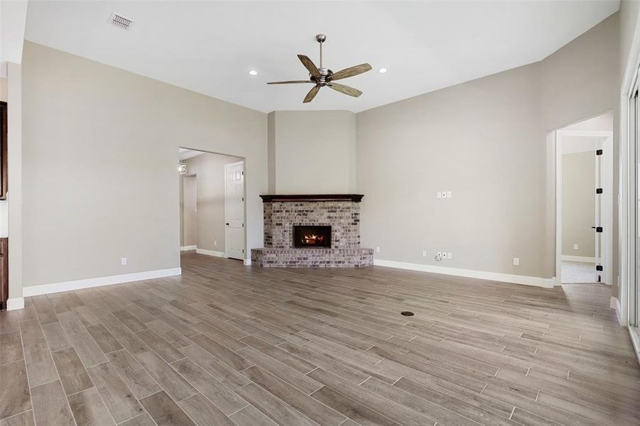 Unfurnished living room with light hardwood / wood-style floors, a fireplace, and ceiling fan