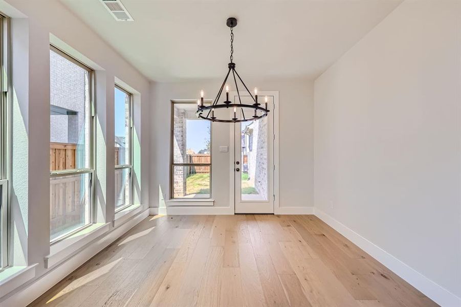 Doorway to outside featuring a notable chandelier and light hardwood / wood-style flooring