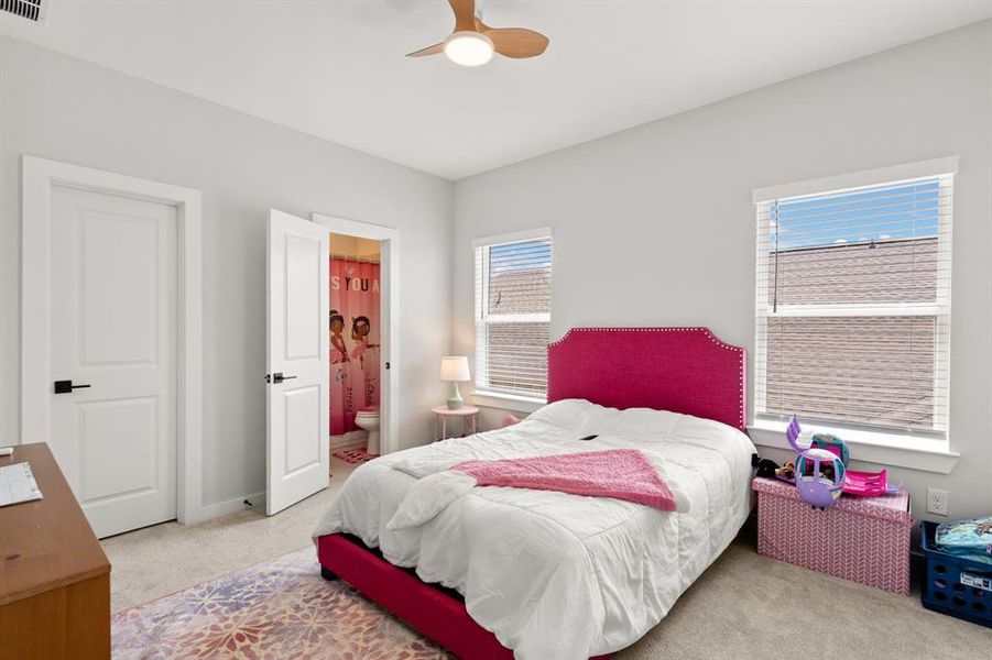 The fifth bedroom features two windows, carpet flooring, and a ceiling fan, providing ample natural light and comfortable airflow.