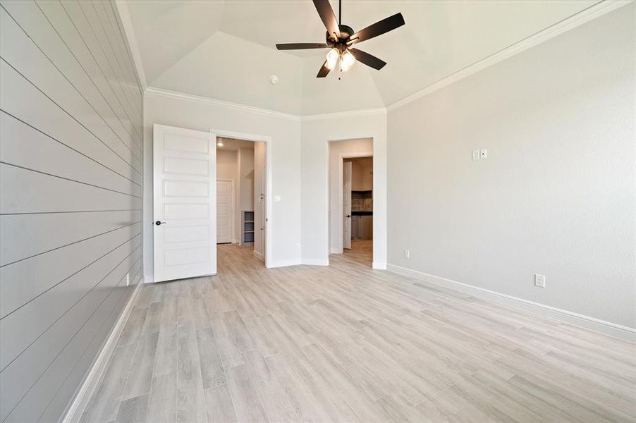 Unfurnished bedroom with lofted ceiling, light hardwood / wood-style floors, crown molding, and ceiling fan