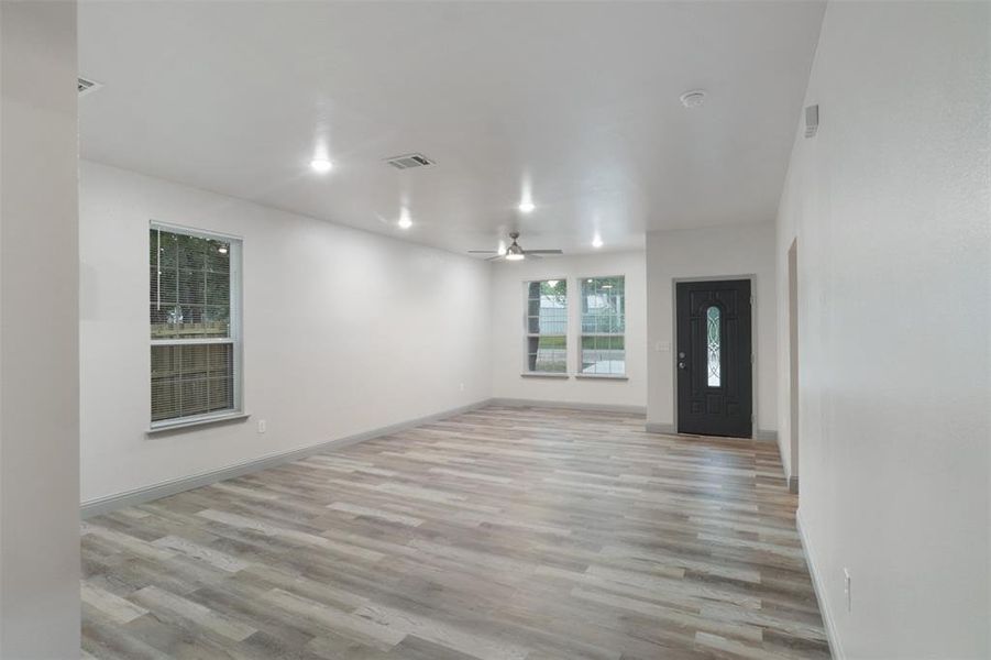 Unfurnished living room with ceiling fan and light wood-type flooring