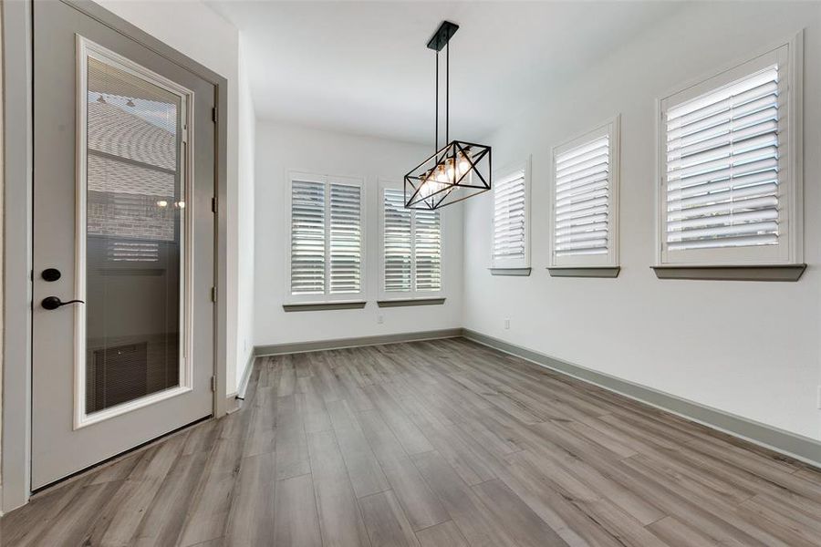 Unfurnished dining area featuring a healthy amount of sunlight, light hardwood / wood-style floors, and a notable chandelier