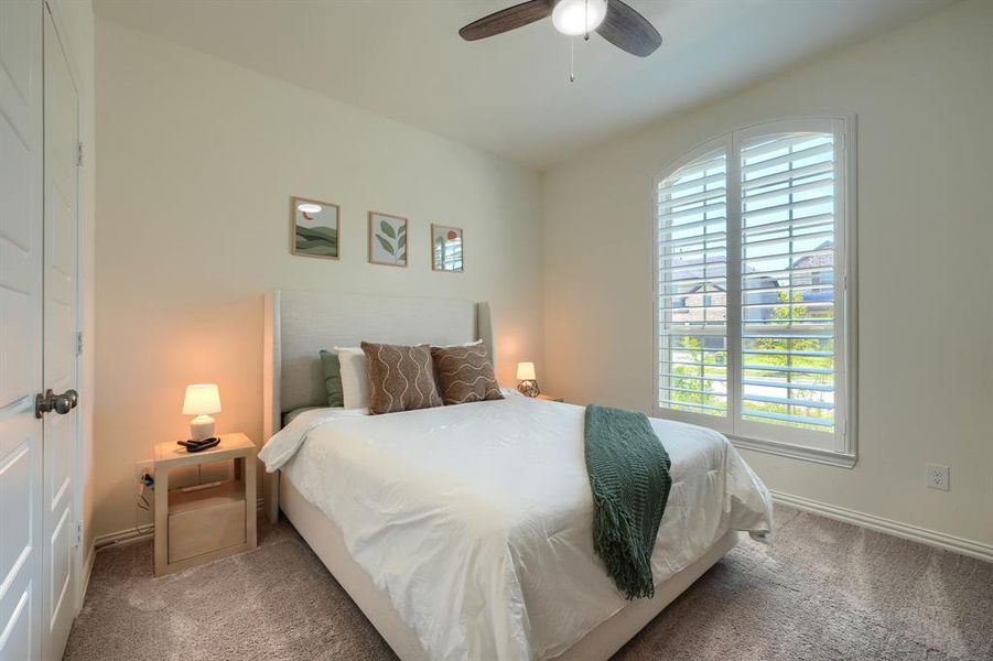 Carpeted bedroom with multiple windows and ceiling fan