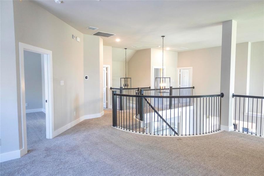 Corridor featuring carpet, lofted ceiling, and a chandelier