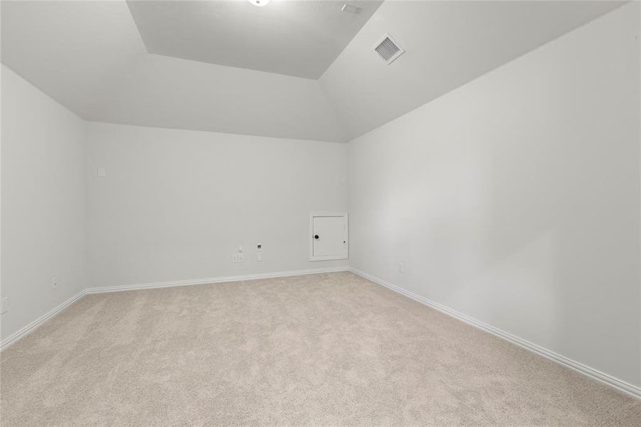 Unfurnished room featuring light carpet and vaulted ceiling