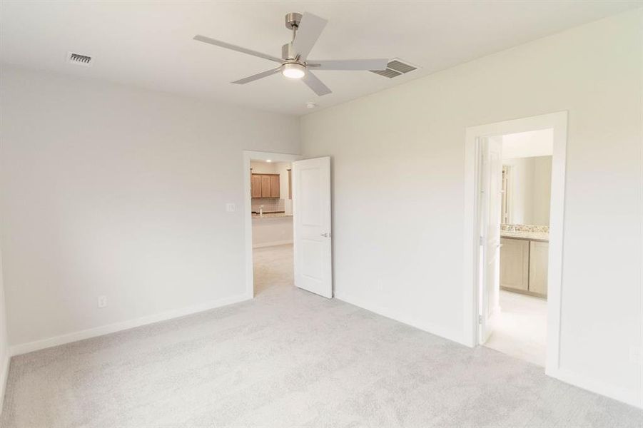 Unfurnished bedroom with ensuite bath, light colored carpet, and ceiling fan
