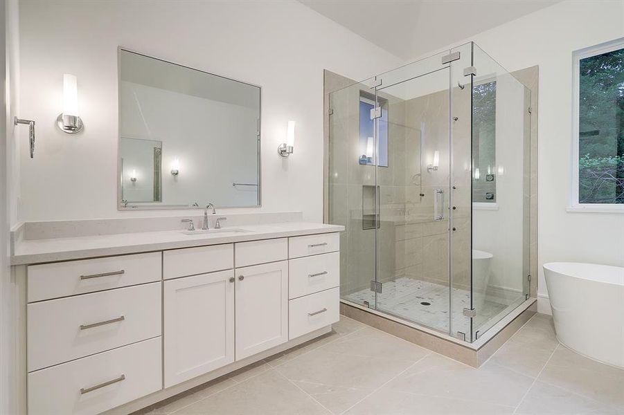 A serene primary bath retreat with his and her dual vanity, seamless glass shower and soaking tub.