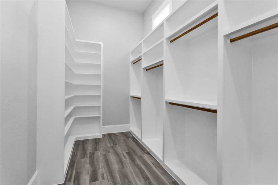 Primary Walk-In Closet #2. Offers a well-placed transom to allow natural light to flow in and is also finished with custom built-ins offering an amazing amount of hang space and shelf space, beautiful moldings and finishings.