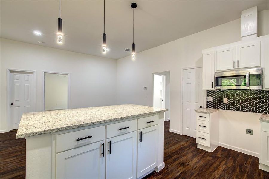 Kitchen with backsplash, white cabinets, dark hardwood / wood-style flooring, and pendant lighting