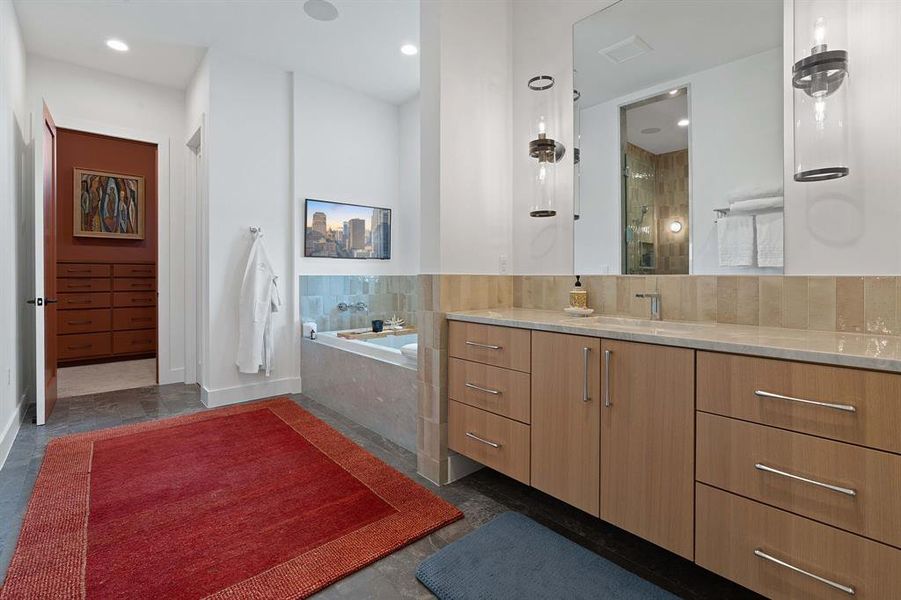 The luxury ensuite bathroom of your dreams with two separate sides connected by the walkthrough walk-in shower. This side boasts the built-in soaking tub and access to one of two custom walk-in closets.