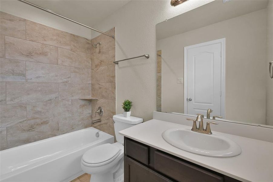 This is a modern bathroom with a neutral color scheme, featuring a tiled bathtub/shower combo, a single sink vanity with counter space, and a large mirror.