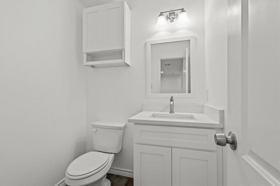 Bathroom featuring toilet, vanity, and wood-type flooring