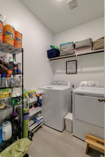 Laundry area with light hardwood / wood-style floors and washer and dryer