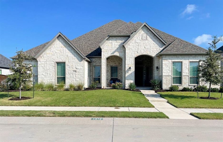 French country inspired facade featuring a front lawn