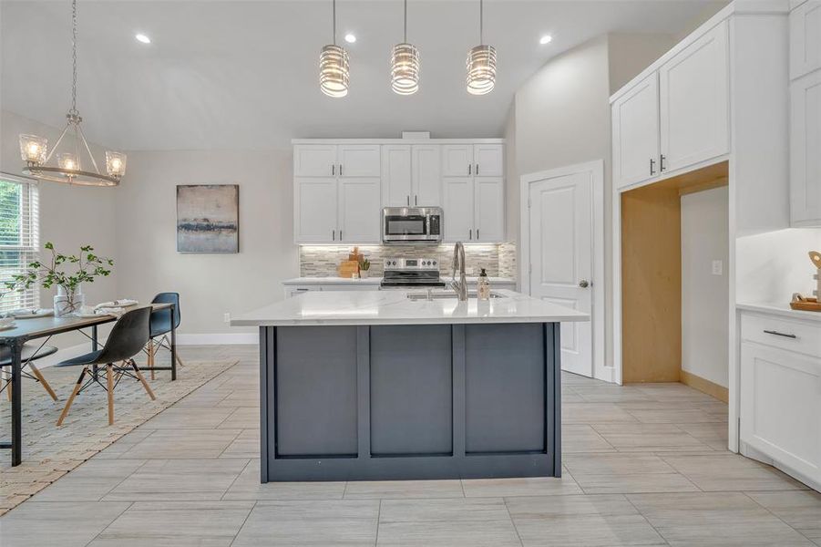 Kitchen featuring light tile patterned flooring, sink, stainless steel appliances, and white cabinets