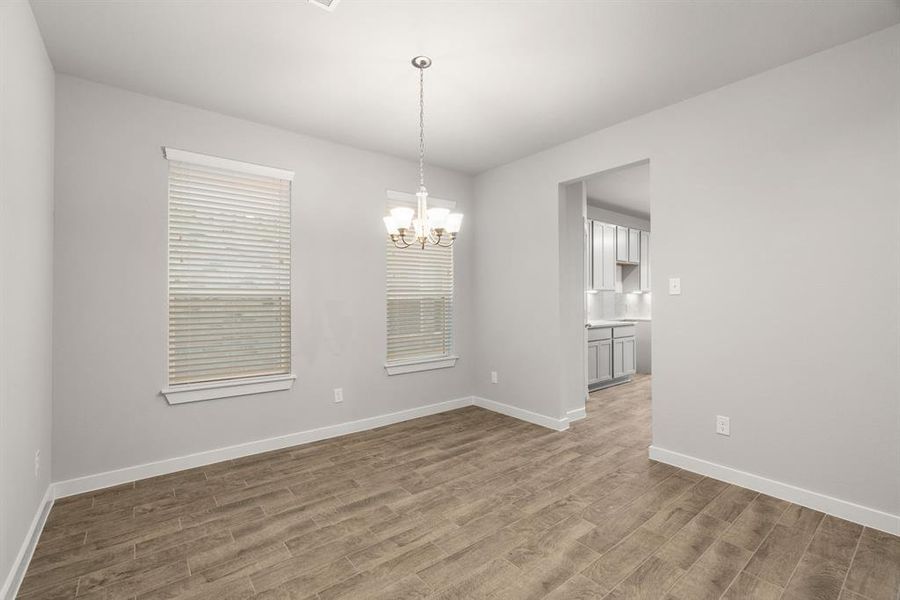 This spacious dining room features elegant flooring, custom paint, and adjacent to family room and kitchen for open concept feel. Sample photo of completed home with similar floor plan. As-built interior colors and selections may vary.