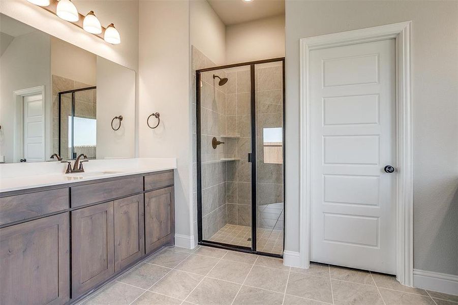 Bathroom featuring tile patterned floors, vanity, and an enclosed shower