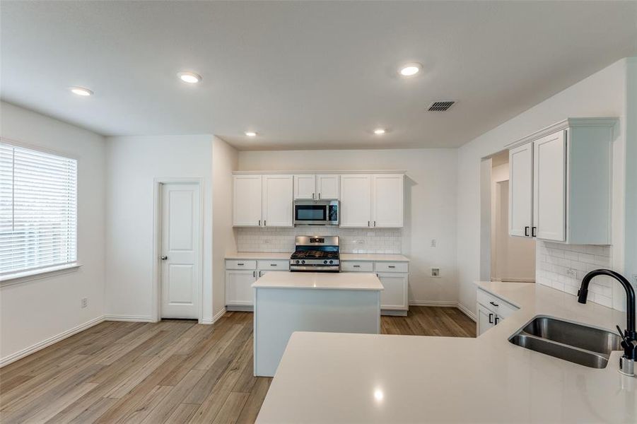 Kitchen featuring stainless steel appliances, white cabinetry, sink, and light wood-type flooring