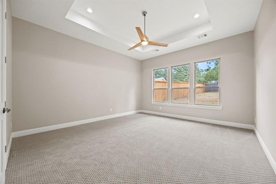 Unfurnished room featuring carpet flooring, ceiling fan, and a raised ceiling
