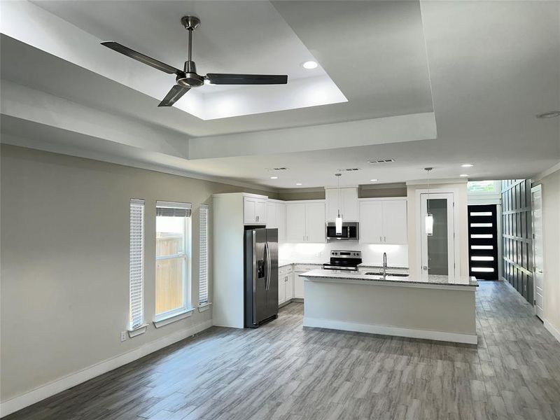 Kitchen with ceiling fan, stainless steel appliances, light wood-type tile flooring, a raised ceiling, and white real wood cabinetry