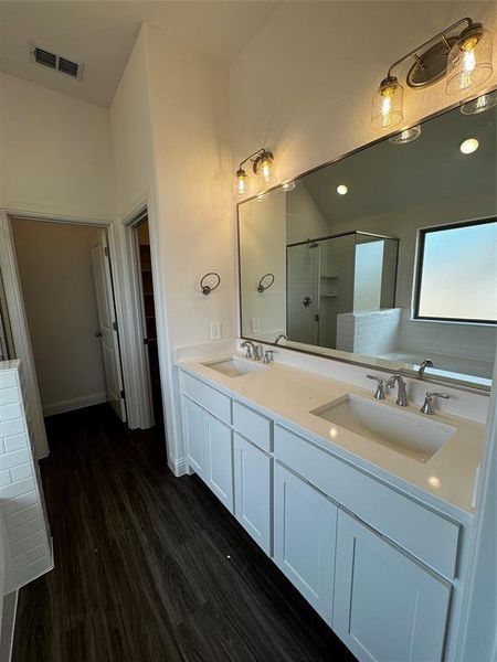 Bathroom featuring double sink vanity, hardwood / wood-style floors, and an enclosed shower