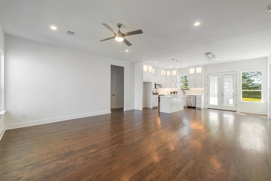 Unfurnished living room with ceiling fan, french doors, and dark wood-type flooring