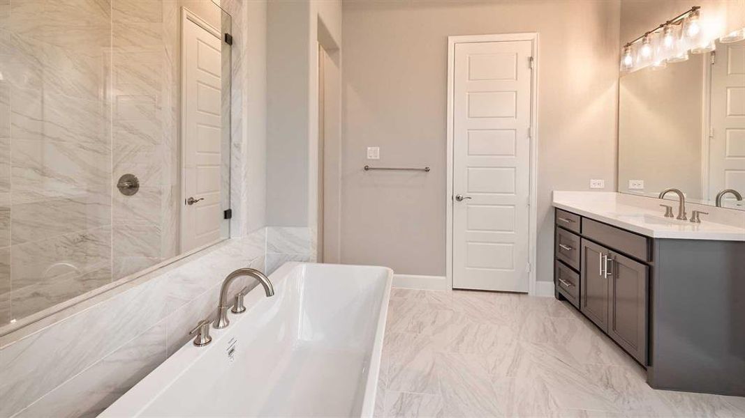 Bathroom with vanity, tile patterned flooring, and a tub