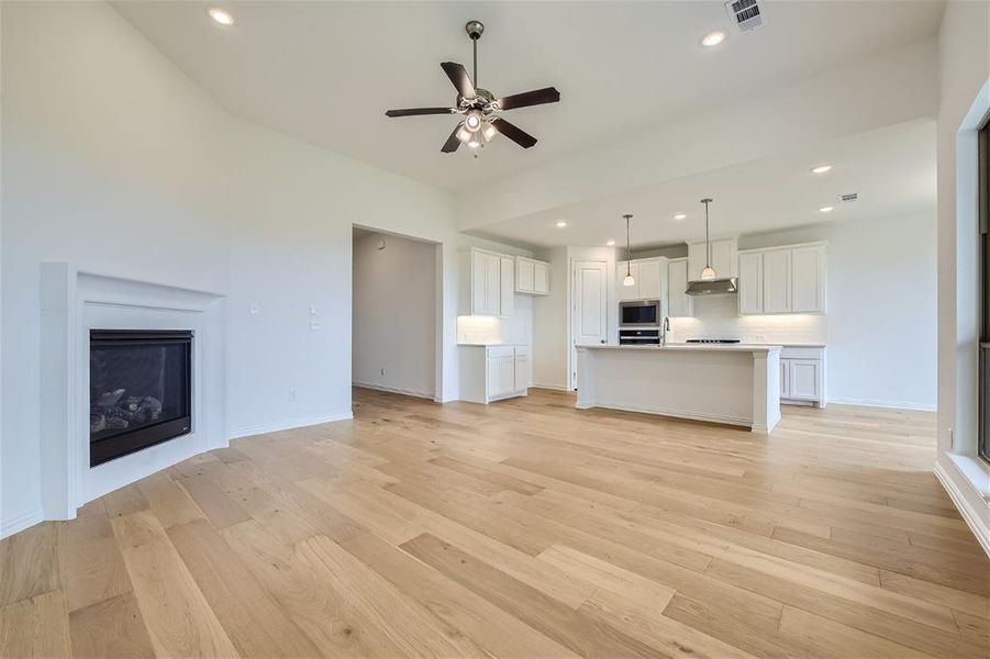 Unfurnished living room with light wood-type flooring and ceiling fan