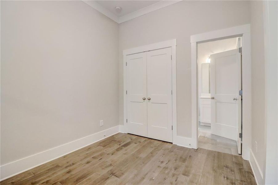 Unfurnished bedroom with ornamental molding, light wood-type flooring, and a closet