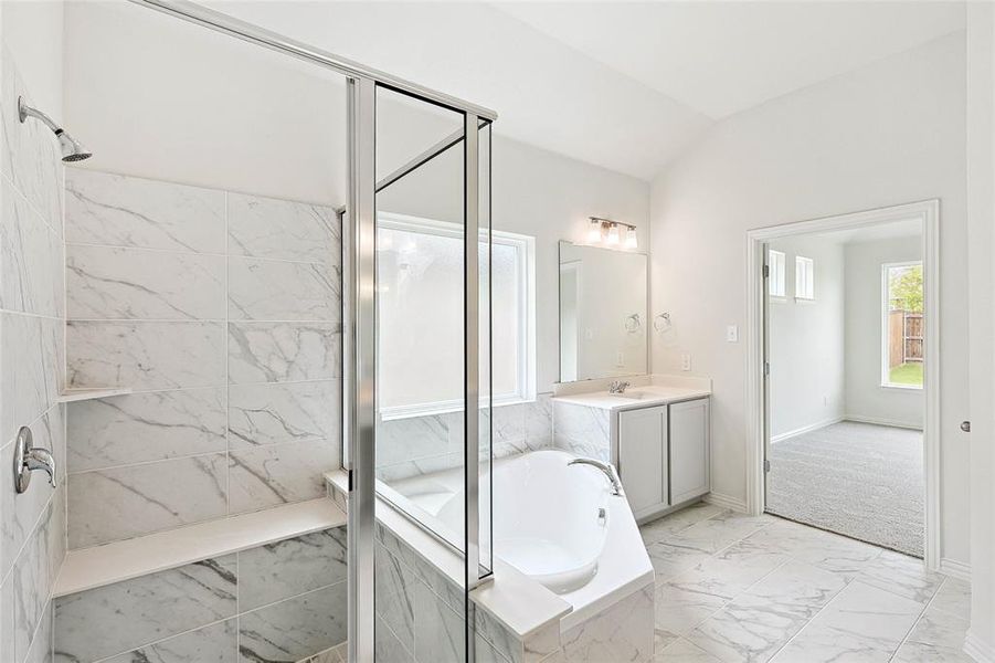 Bathroom with vaulted ceiling, independent shower and bath, oversized vanity, and tile flooring