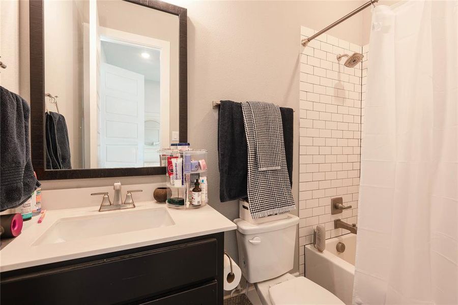 Full bathroom featuring vanity, toilet, and shower / bathtub combination with curtain