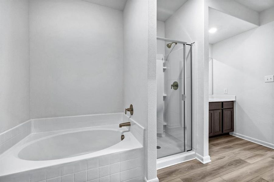 Bathroom featuring vanity, hardwood / wood-style flooring, and shower with separate bathtub