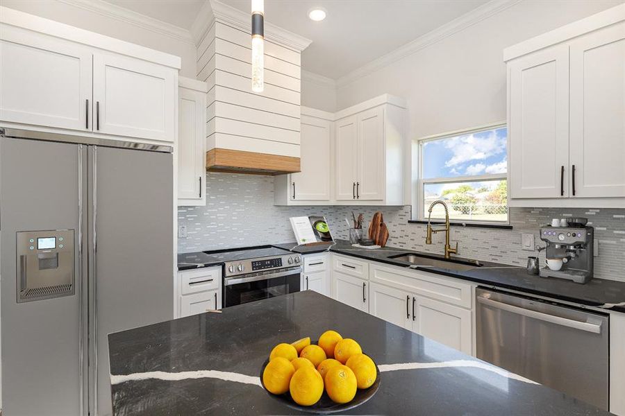 Kitchen featuring ornamental molding, sink, white cabinetry, appliances with stainless steel finishes, and decorative backsplash