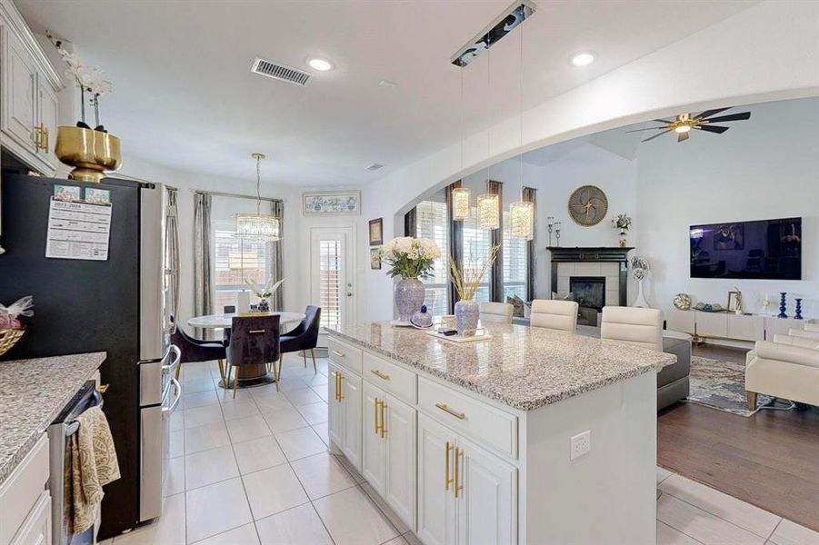 Kitchen with a center island, pendant lighting, white cabinetry, appliances with stainless steel finishes, and light hardwood / wood-style floors