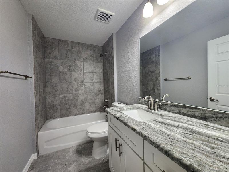 Guest Bathroom with tub/shower combo, ceramic tile walls and granite countertops