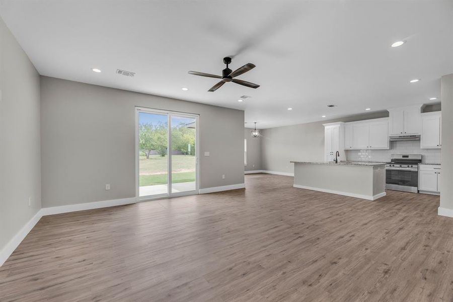 Unfurnished living room featuring ceiling fan, sink, and light hardwood / wood-style flooring