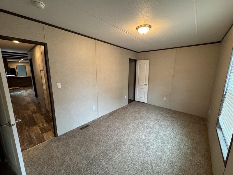 Unfurnished bedroom featuring dark carpet and crown molding