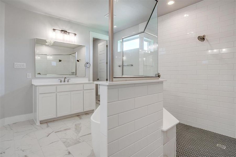 Bathroom featuring tile patterned floors, vanity, and a tile shower