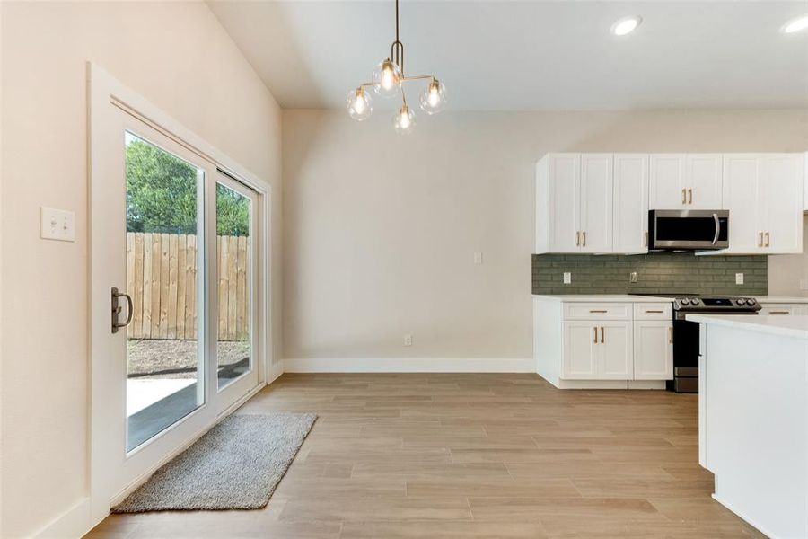 Kitchen featuring white cabinets, decorative light fixtures, a chandelier, stainless steel appliances, and light hardwood / wood-style floors