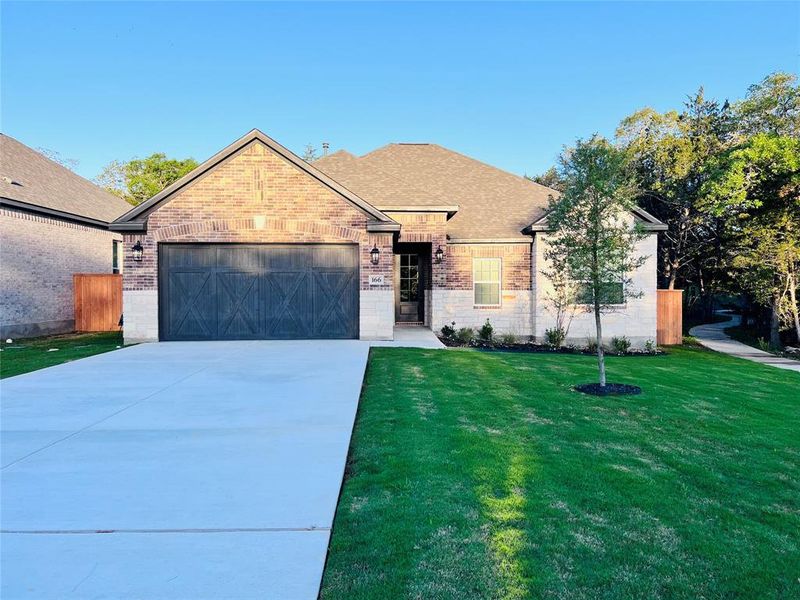 The Hendrie plan at The Colony is a beautiful single-story home with a long driveway, gorgeous cedar garage door, and lush front yard landscaping.