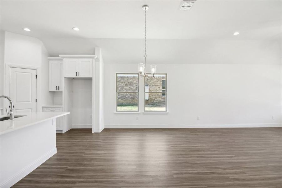 Kitchen featuring a chandelier, sink, white cabinets, hanging light fixtures, and dark hardwood / wood-style flooring