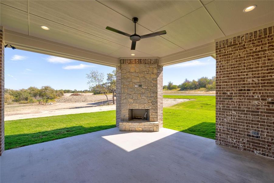 View of patio / terrace with ceiling fan and an outdoor stone fireplace