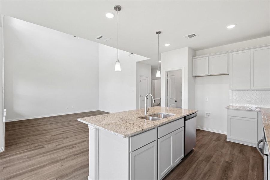 Kitchen featuring backsplash, dishwasher, hardwood / wood-style flooring, an island with sink, and sink