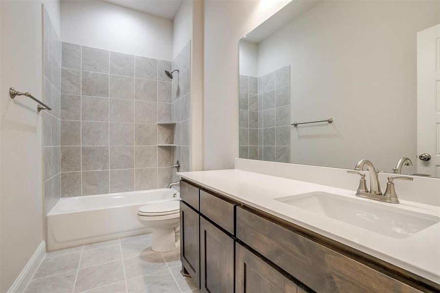 Full bathroom featuring tile patterned flooring, vanity, toilet, and tiled shower / bath