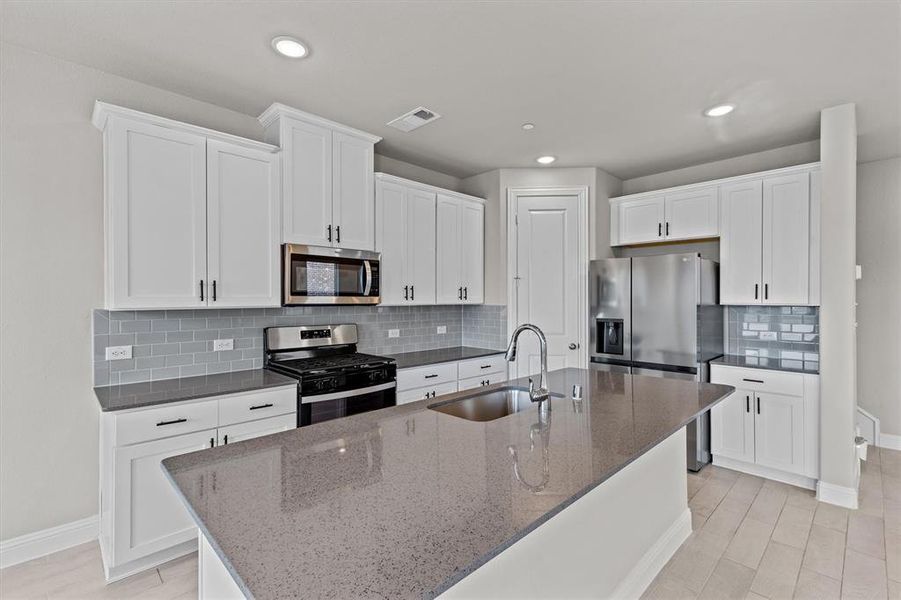 Kitchen with appliances with stainless steel finishes, white cabinetry, sink, and a center island with sink